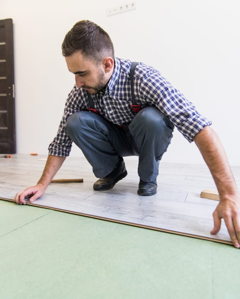 Young worker laying a floor with bright laminated flooring boards